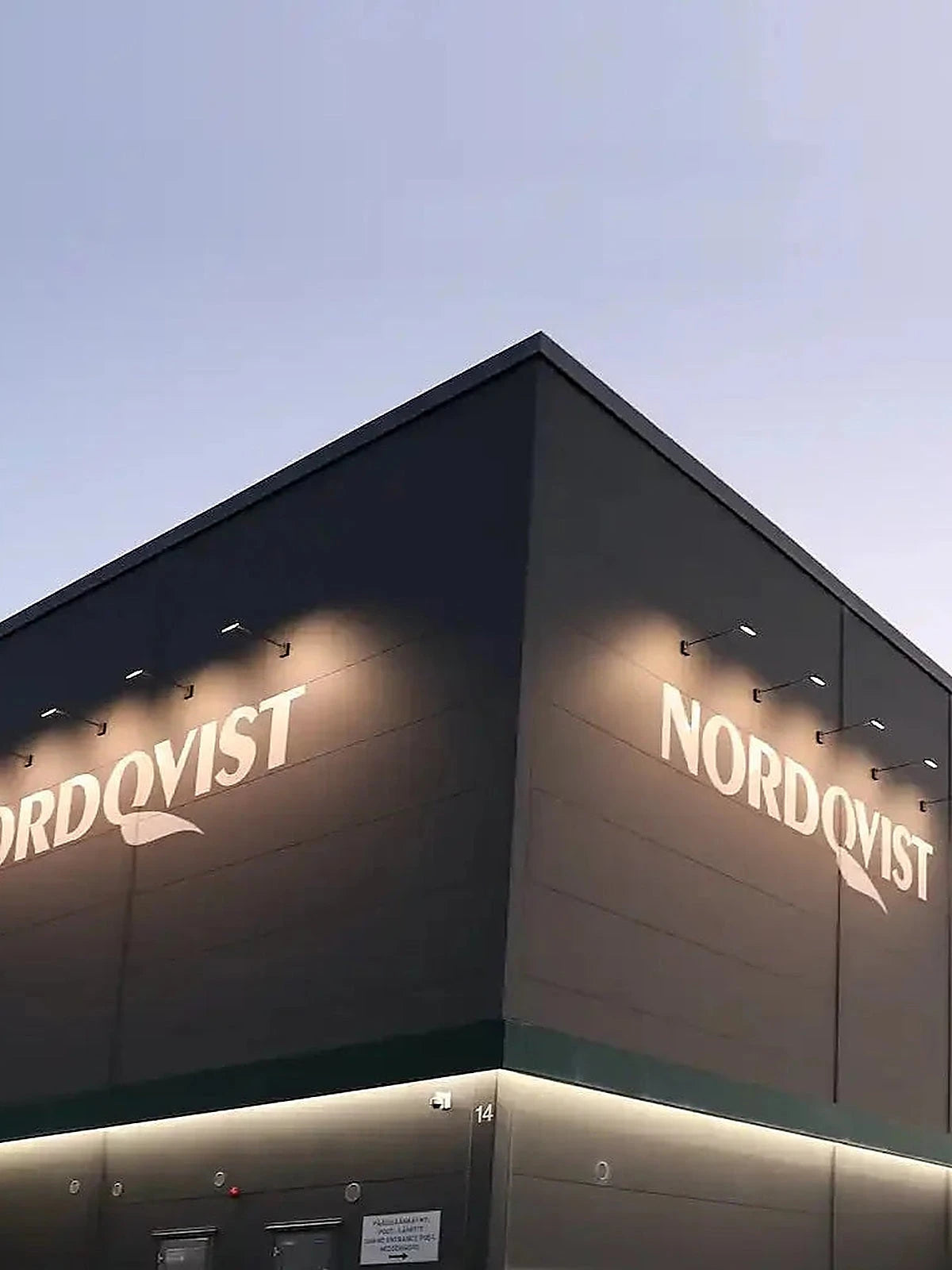 Nordqvist headquarters building with illuminated logo at dusk