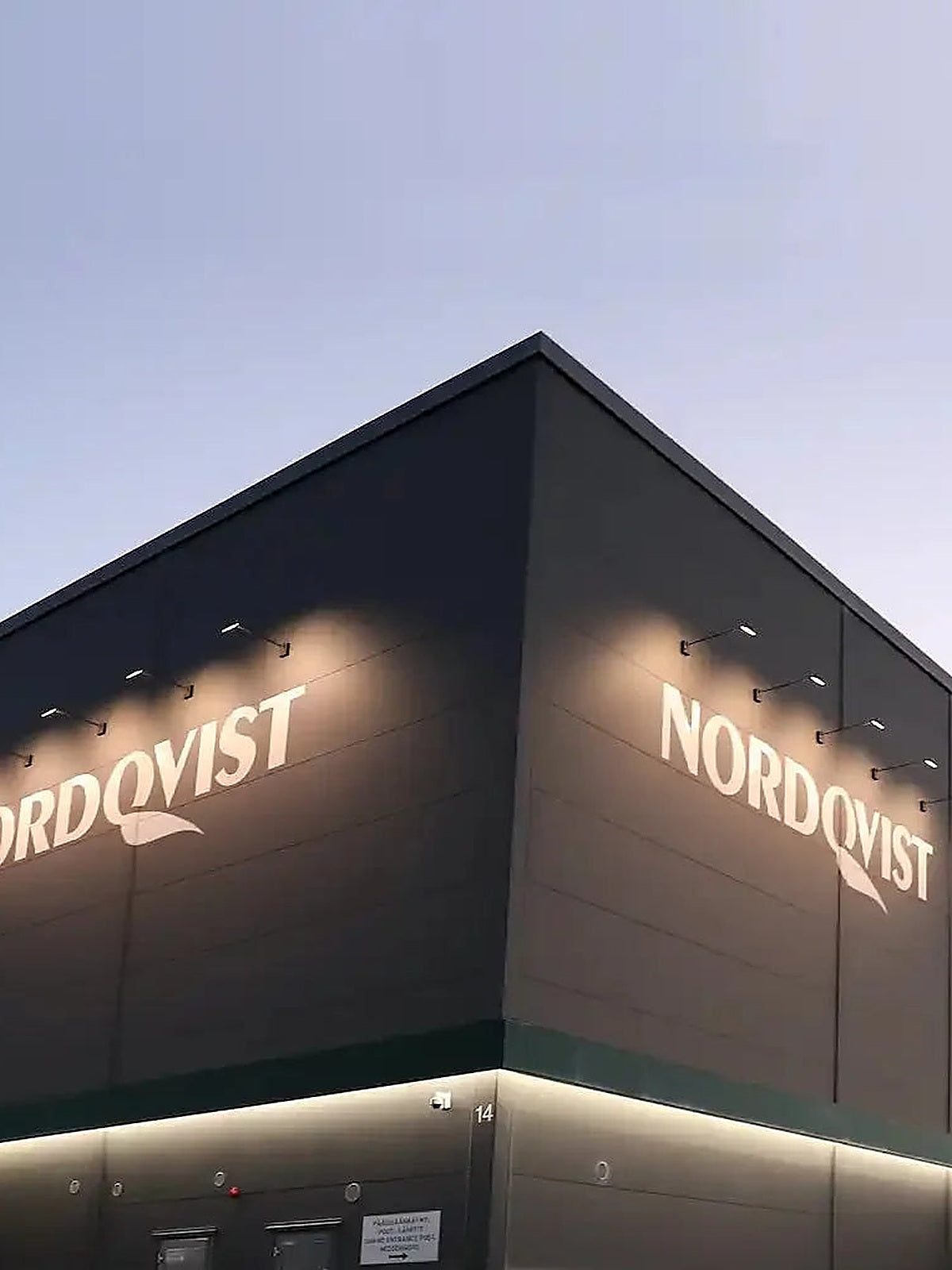 Nordqvist headquarters building with illuminated logo at dusk